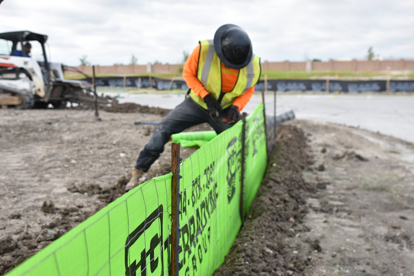 Terradyne crew driving posts for a branded silt fence along a site perimeter