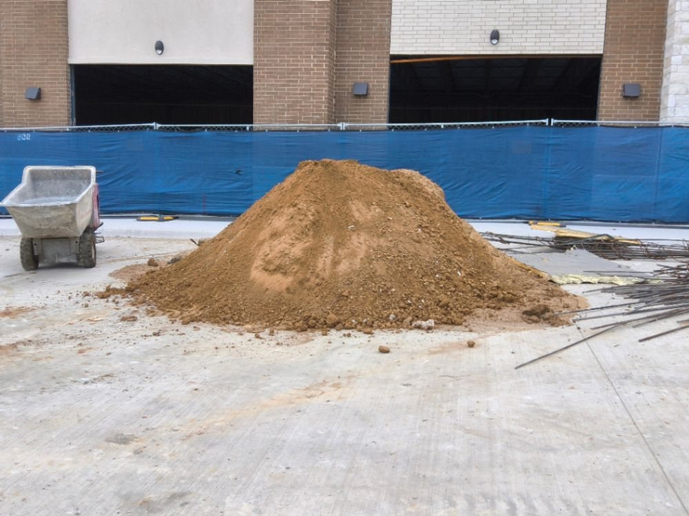 Soil stockpile staged behind construction fencing on an Allen retail build