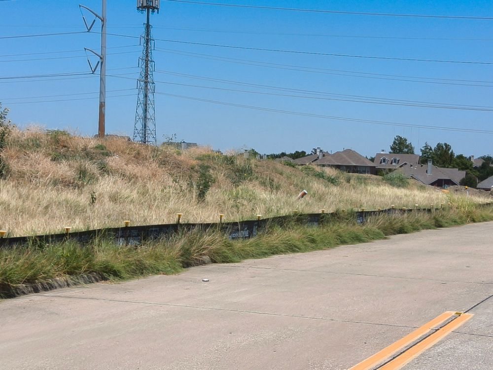 Silt fence with capped posts along a vegetated slope on an Irving development