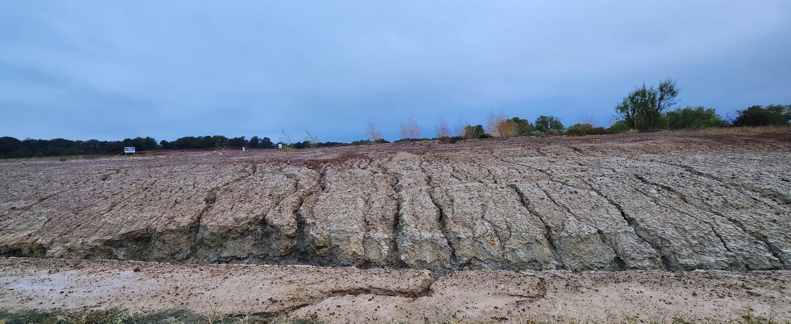 Rain-cut rills across bare clay showing why controls need maintenance between inspections