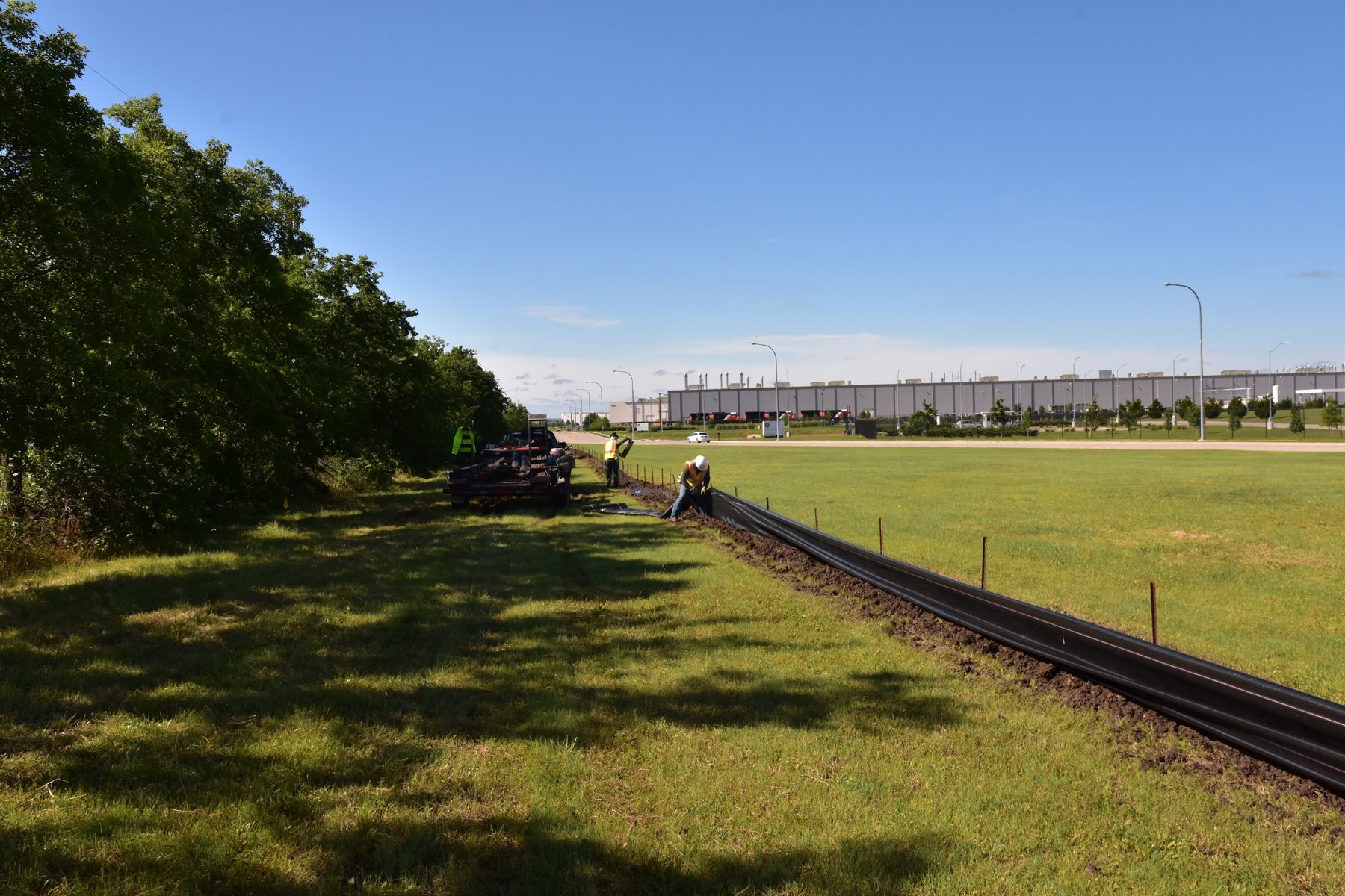 Crew installing a new silt fence line along an open field