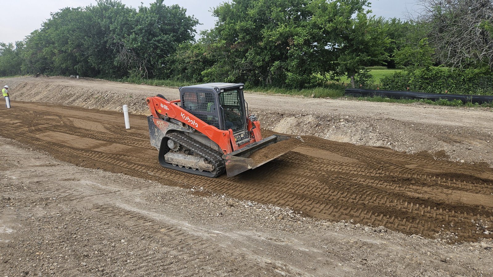 Compact track loader grading a construction pad
