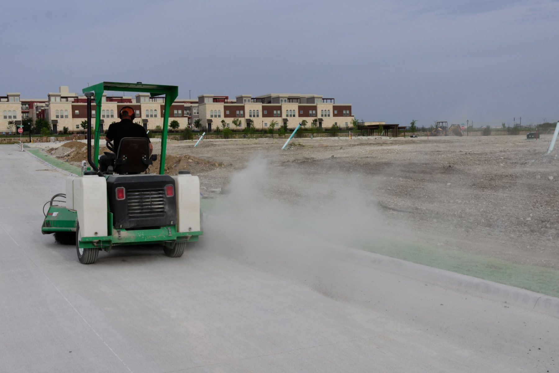 Street sweeper clearing track-out from a public street beside an active site