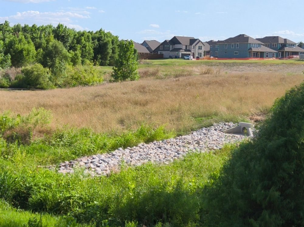 Rip-rap outfall apron below a headwall, discharging to a vegetated swale